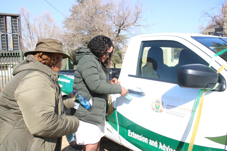 Twee vroulike landbouvoorligtingsbeamptes by 'n nuwe Isuzu-bakkie.